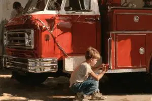 Young boy helping clean a fire truck, illustrating how childhood service helped shape heroes like Welles Crowther.