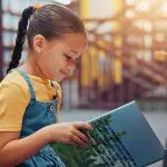 Young reader enjoying a book in a library while building confidence and a love of reading.