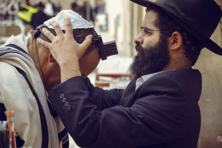 Jewish men wearing tefillin during prayer connected to the Shema Yisrael and Deuteronomy 6 covenant teachings