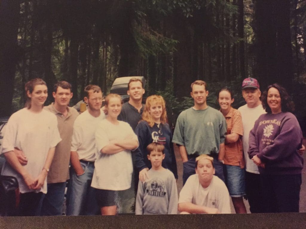 A large, extended family posing together at a reunion in the woods, showcasing the joy of gathering and strengthening family bonds.