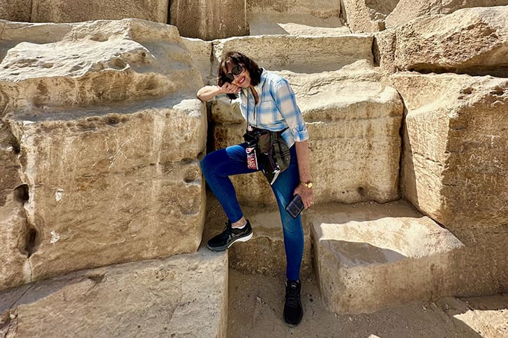 Maurine rests on the ancient stones of the Great Pyramid, showcasing the scale of the limestone blocks and the grandeur of this ancient structure.