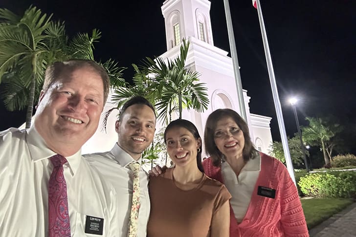 The Proctors and local Saints stand in front of the Puerto Rico temple at night, capturing the warmth and camaraderie shared on their mission.