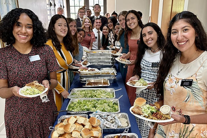 LDS missionaries enjoy a meal together, illustrating the strong bonds formed through shared experiences and love for the people they serve.