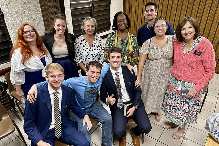 Group of missionaries and church members gathered in a church meeting room in Puerto Rico.