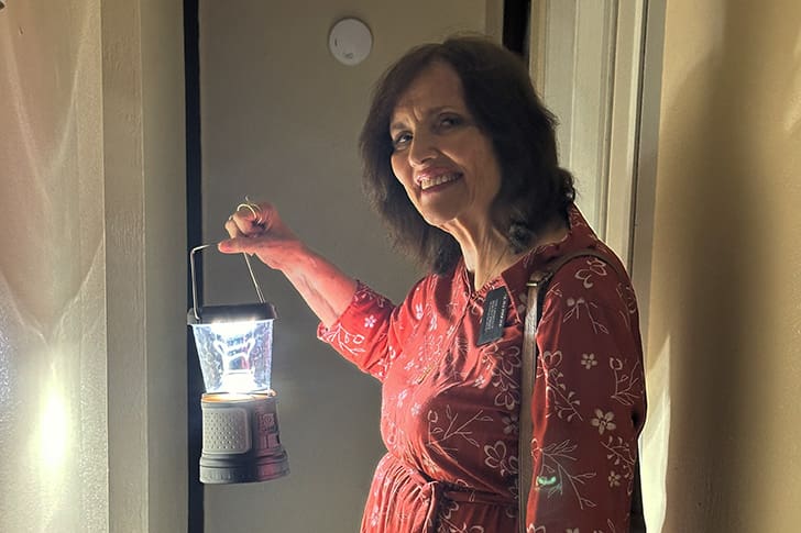 Maurine holds a lantern during a power outage, symbolizing resilience and faith in challenging circumstances in Puerto Rico.