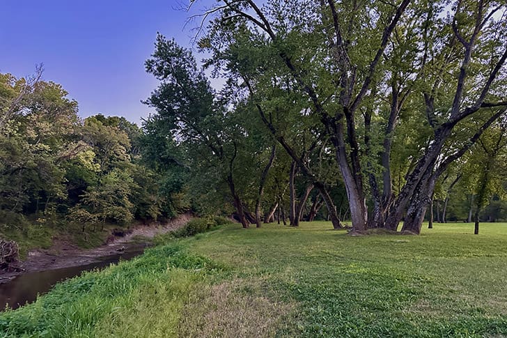 The peaceful banks of Shoal Creek, surrounded by towering trees, as it winds through Hawn’s Mill, the site of the tragic massacre of Latter-day Saints.