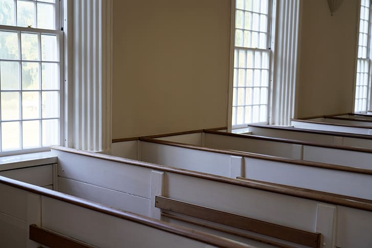 Sunlit windows and wooden pews in the Kirtland Temple, capturing the serene beauty of the sacred space used by early Saints.
