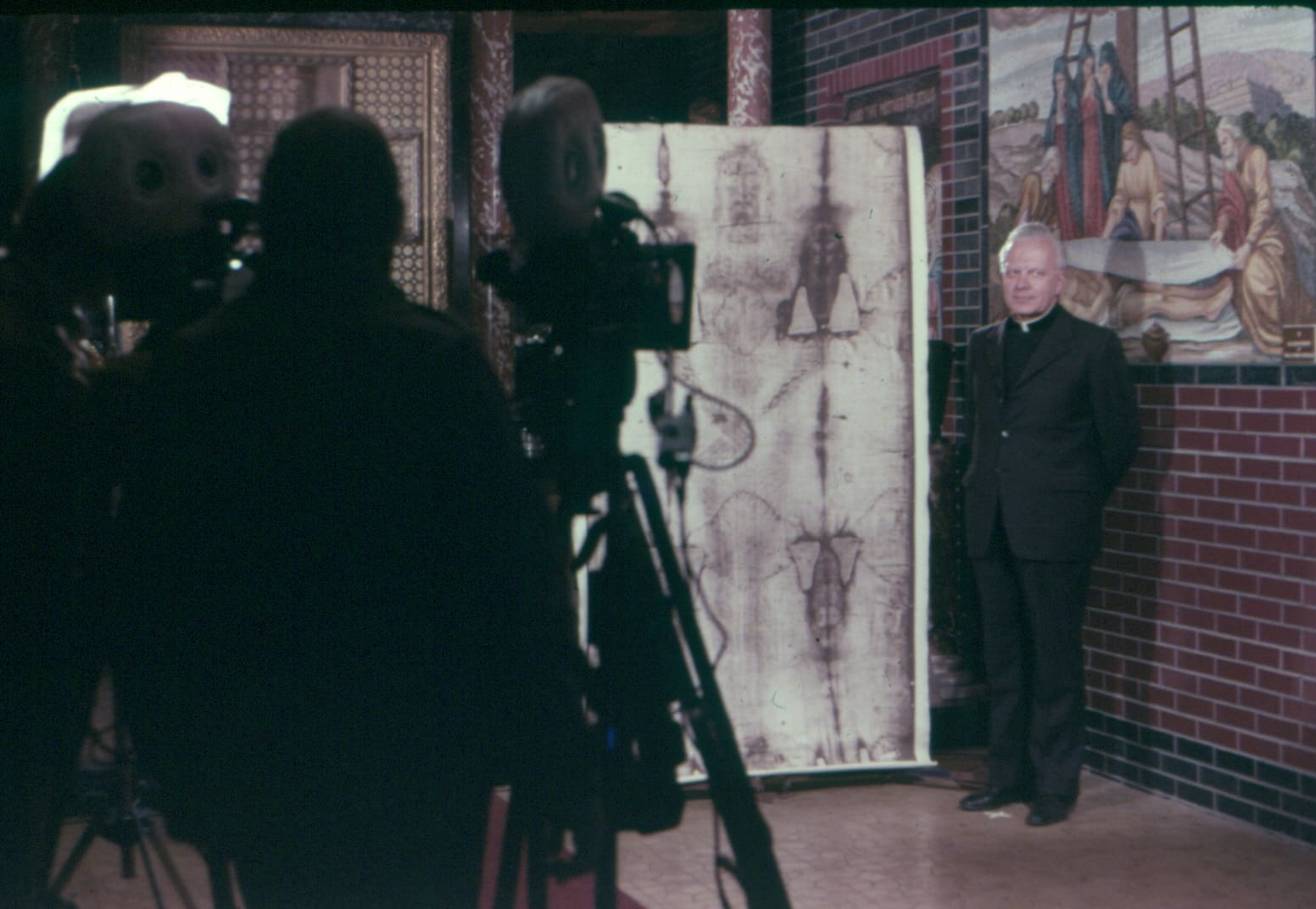 Cameras filming the Shroud of Turin with a religious scholar discussing its significance and connection to Christian beliefs