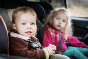 Two children secured in car seats, representing the importance of commitment over compliance in ensuring safety and purpose-driven actions.