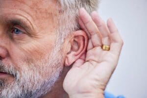 Older man cupping his ear, emphasizing attentive listening and empathy for meaningful communication and connection.