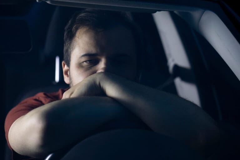 Man sitting in a car at night, reflecting on life’s challenges and finding hope in faith.
