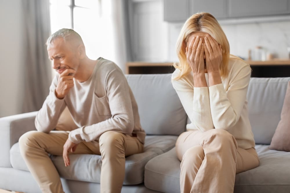 Distressed couple on a couch dealing with marital challenges and emotional disconnect.