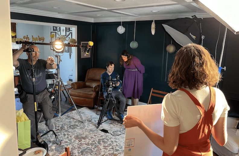 Filmmakers on set of Two Heartbeats, preparing lighting and camera for a modern baby shower scene.