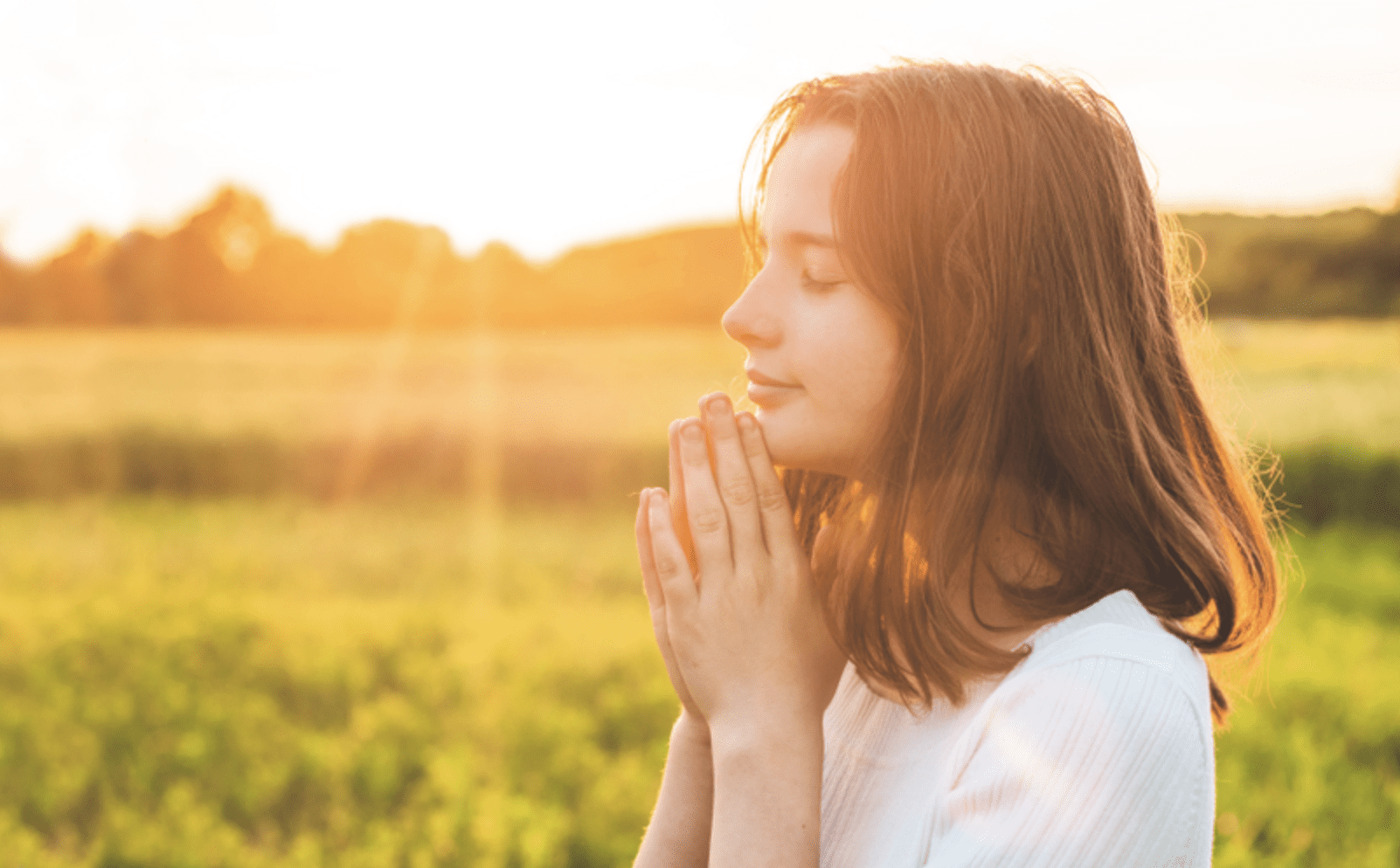 Young woman praying in a field, seeking personal revelation and divine answers.