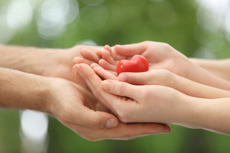 Hands holding a red heart, symbolizing charity, selfless love, and kindness, illustrating the pure love of Christ.