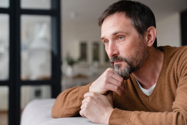 Thoughtful middle-aged man contemplating life, symbolizing the emotional journey of LDS mid-singles after divorce.