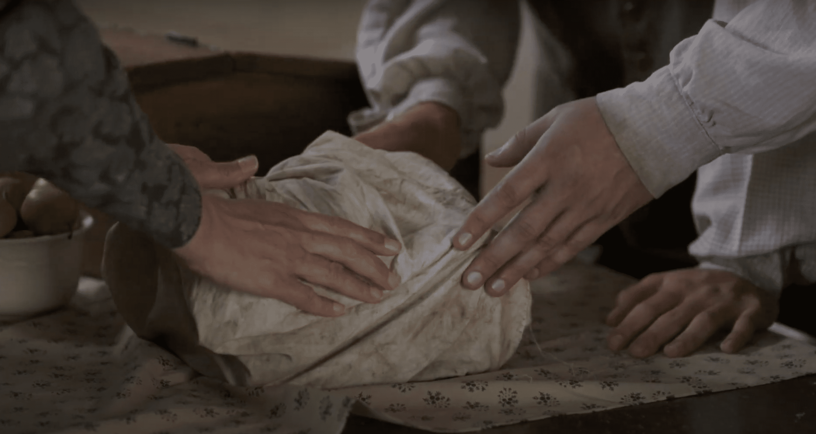 Hands carefully handling a wrapped object, representing the gold plates of the Book of Mormon, as described by unofficial witnesses.