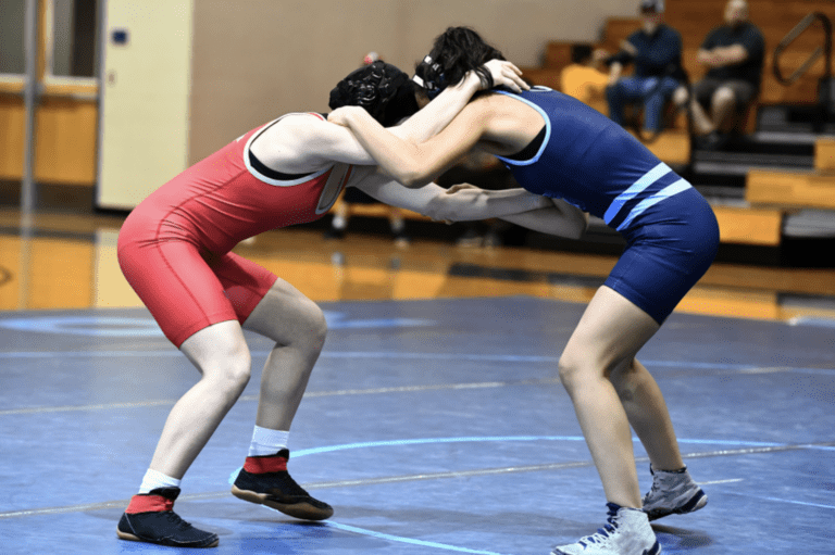 Two high school wrestlers engaged in a match, demonstrating skill, strength, and determination in a varsity competition.
