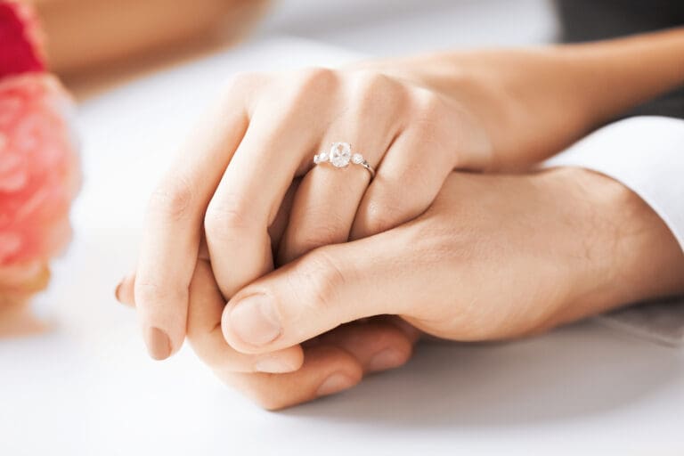 Couple holding hands with an engagement ring, representing eternal marriage and temple sealing in LDS doctrine.