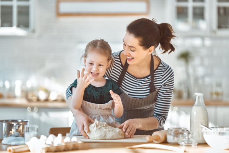 Mother teaching her daughter how to bake, reinforcing essential life skills in the kitchen.