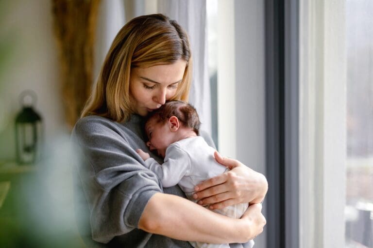Mother holding newborn baby, representing emotional healing and family transitions in blended families.
