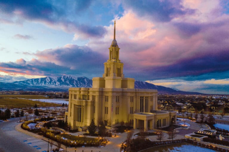 LDS temple at sunset with snowy grounds and mountain views, symbolizing the eternal blessings of temple work and salvation.