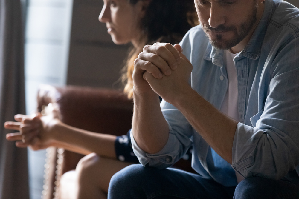 Emotionally distant married couple sitting apart in silence, showing signs of relationship disconnection and tension.