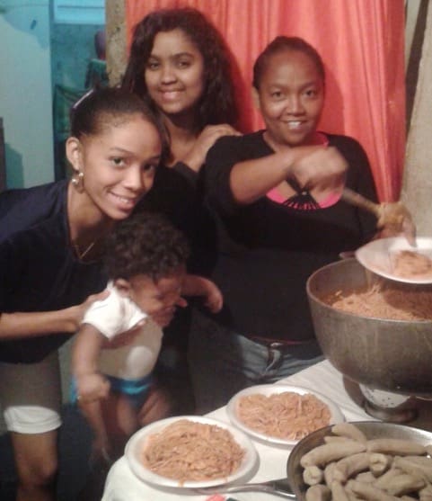 Three Dominican women and a young child serve food in a humble home as part of a story of generosity and compassion toward Elder Perez’s mentally ill mother, illustrating the love and sacrifice of Latter-day Saint members in the Dominican Republic.