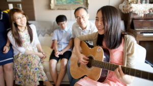Latter-day Saint family singing and playing guitar at home, illustrating joyful worship with new global hymnbook “Hymns—For Home and Church.”