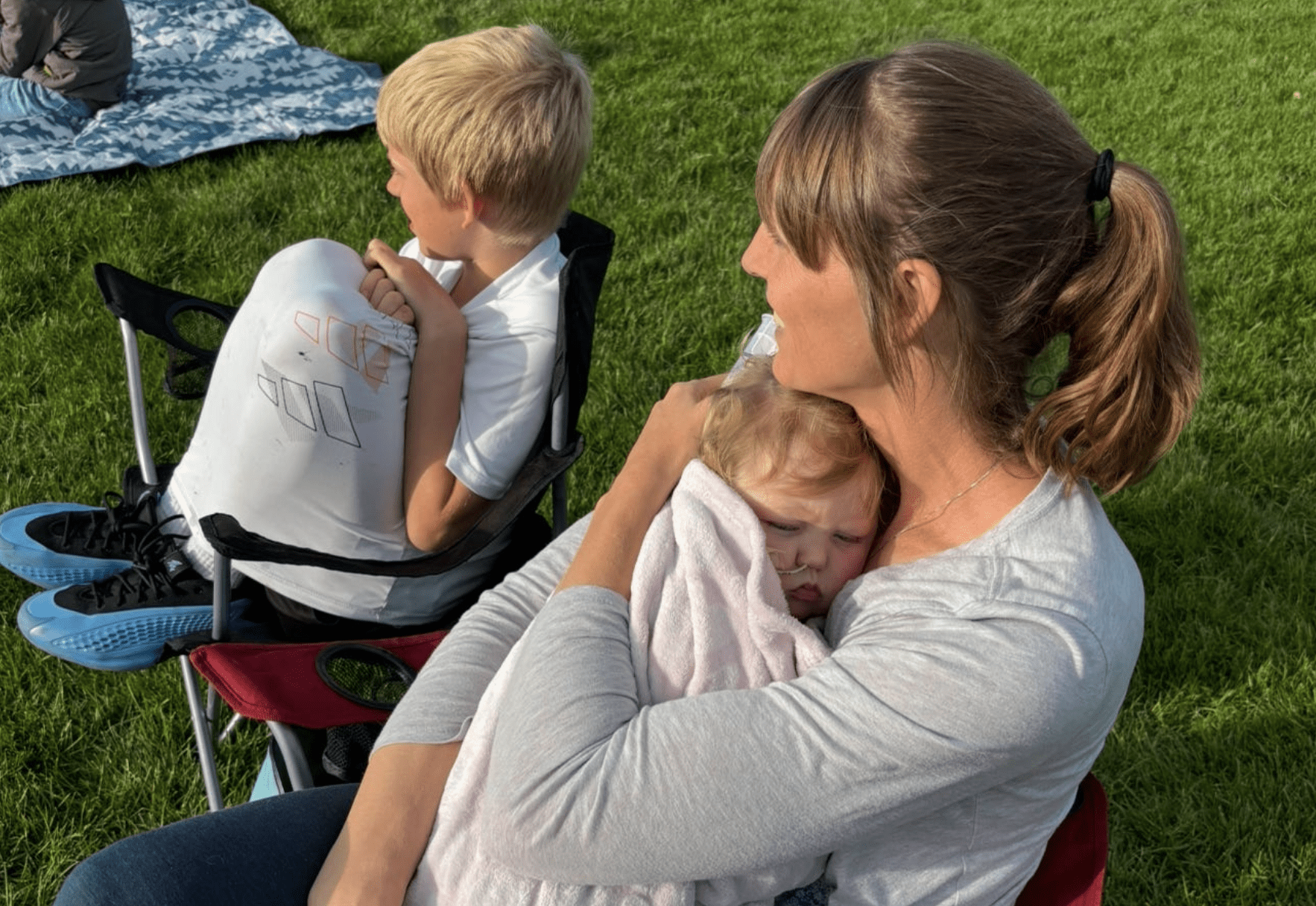 Mother holding baby on her chest next to son, illustrating faith, comfort, and spiritual strength in motherhood