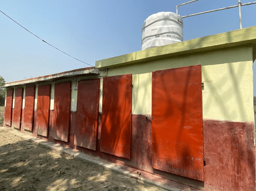 A row of modern toilets with a water storage tank, completed as part of a community sanitation service project in a rural Indian village.