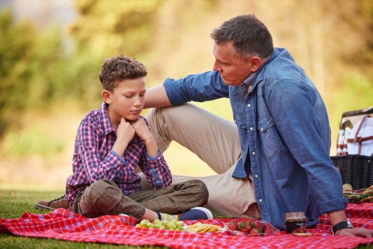 Father comforting son during a heartfelt conversation outdoors, demonstrating generative fathering and responsive parenting.