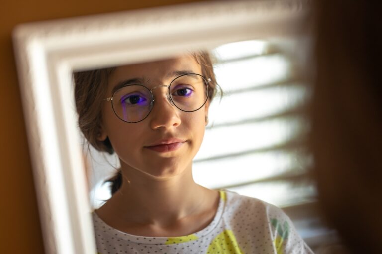 Teenager with glasses looking in mirror, representing youth identity and concerns around gender ideology