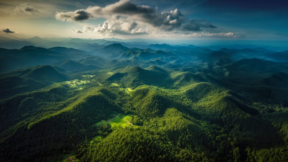 Aerial view of lush green mountains and valleys under glowing light, symbolizing the peace and glory of the spirit world.