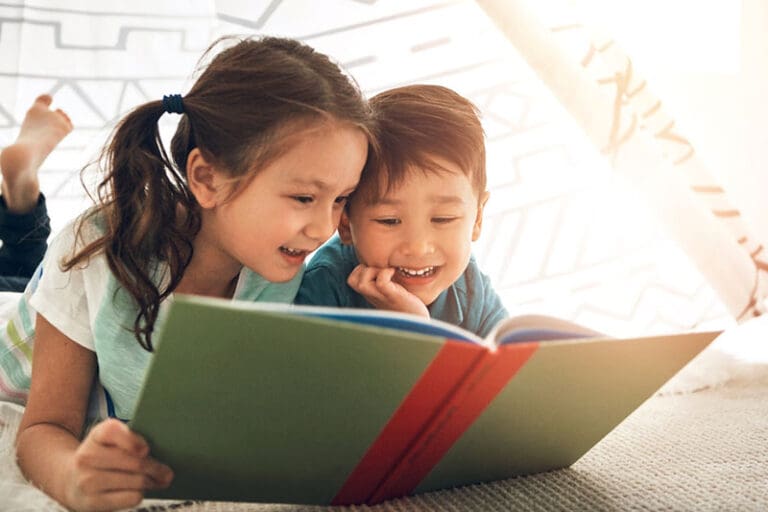 Children reading a colorful picture book together during summer