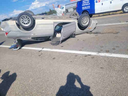 An overturned car rests upside down on a busy highway following a severe collision described in Daris Howard’s article. The image shows the aftermath of the accident that injured two teens and the author, highlighting the dangers of reckless driving and the power of survival.