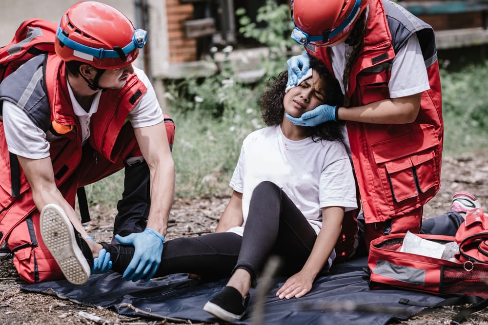 First responders aiding an injured woman after a disaster, representing caring for disaster survivors.