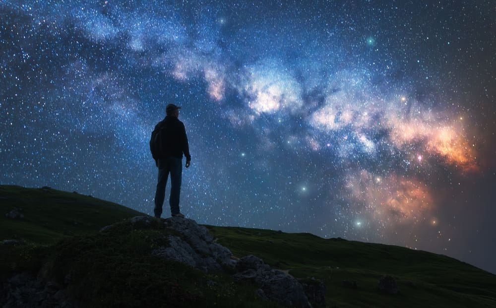 Man looking at the Milky Way galaxy at night, symbolizing faith, divine creation, and a valiant testimony of Jesus Christ (D&C 76)