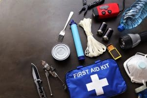 Emergency preparedness kit with first aid, water, flashlight, rope, batteries, and supplies — preparing every needful thing for disasters.