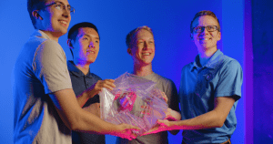  BYU student Kelvin Wang with fellow researchers holding an origami bloom pattern prototype developed through origami engineering research.