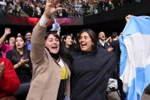 Audience members cheer with joy, waving the Argentine flag during the Tabernacle Choir concerts in Buenos Aires, celebrating faith and connection.