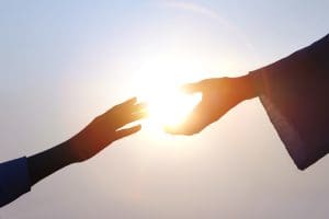 Hands reaching for light symbolizing peace, compassion, and Christlike love after Charlie Kirk’s assassination.