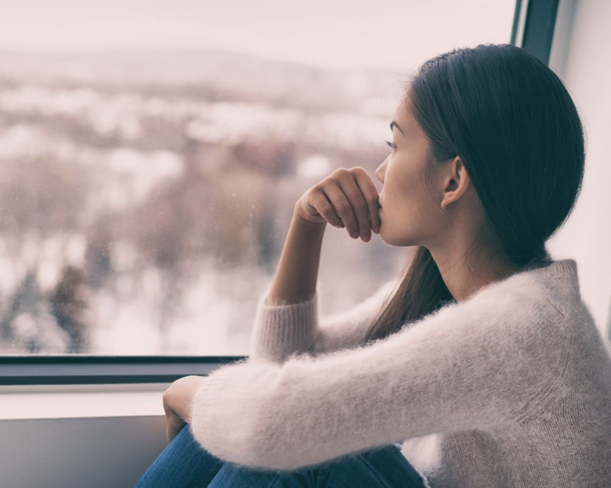 Woman looking out window reflecting on the divine, spiritual longing, and the human desire for God as discussed in Daniel C. Peterson’s article.