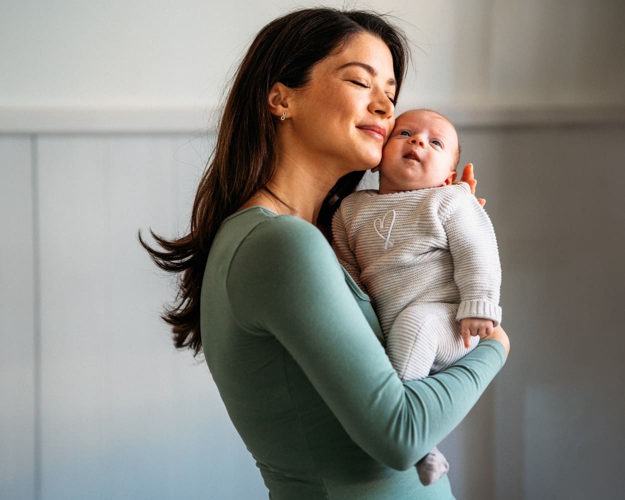Mother tenderly holding newborn baby, reflecting family, love, and faith in Christ.