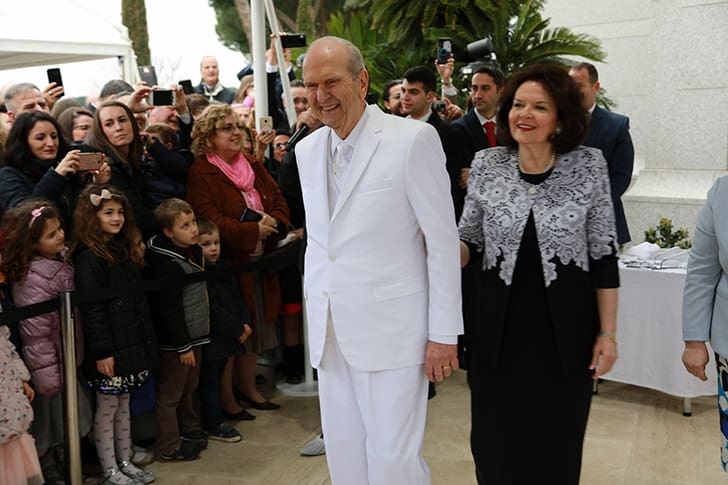 President Russell M. Nelson and his wife, Sister Wendy Nelson, warmly greet Saints and children gathered outside a temple, exemplifying his Christlike leadership and emphasis on temple covenants.