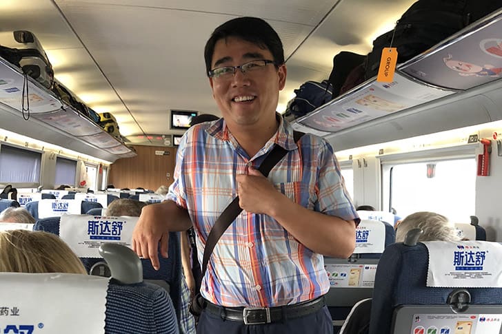 A Chinese tour guide smiles on a high-speed train, later sharing a memorable experience with President Russell M. Nelson, whom he described as “the nicest man” he had ever met.