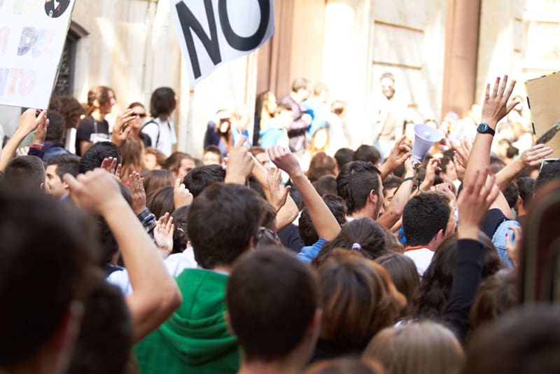 Crowd of protesters holding signs during civil unrest, demonstrating the unpredictable rise of riots and the need for emergency preparedness