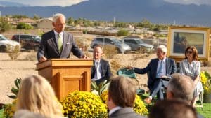Elder Michael A. Dunn addresses Church members at the Lone Mountain Nevada Temple groundbreaking, with Church leaders seated behind him.