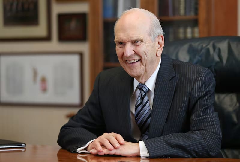 President Russell M. Nelson smiling at his desk as prophet and leader of The Church of Jesus Christ of Latter-day Saints.