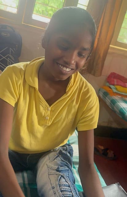 Lakshmi sits smiling on her bed at Rising Star Outreach after returning from New Delhi, fully recovered and full of hope — a radiant outcome of the Lakshmi leprosy miracle.